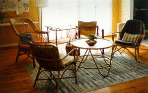 Fyra korgstolar runt ett glasbord i ett solbelyst rum